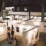 Art exhibition showcasing diverse paintings and installations in a spacious Budapest gallery.